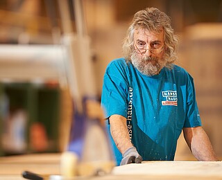 Mann beim zuschneiden eines Holzbalkens im Werk von Hanse Haus