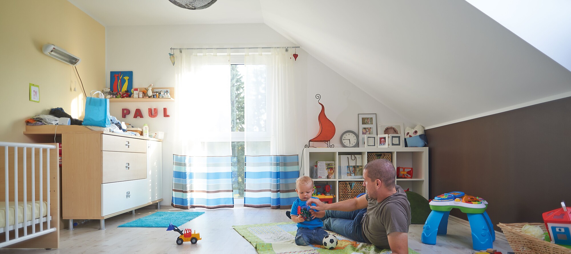 Vater und KInd spielen in einem Kinderzimmer in einem Fertighaus erbaut von Hanse Haus