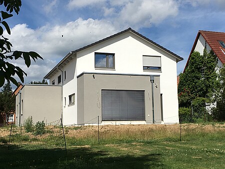 Das Haus von Familie Limberg - Weißes Haus mit Satteldach mit grauem Flachdachanbau 